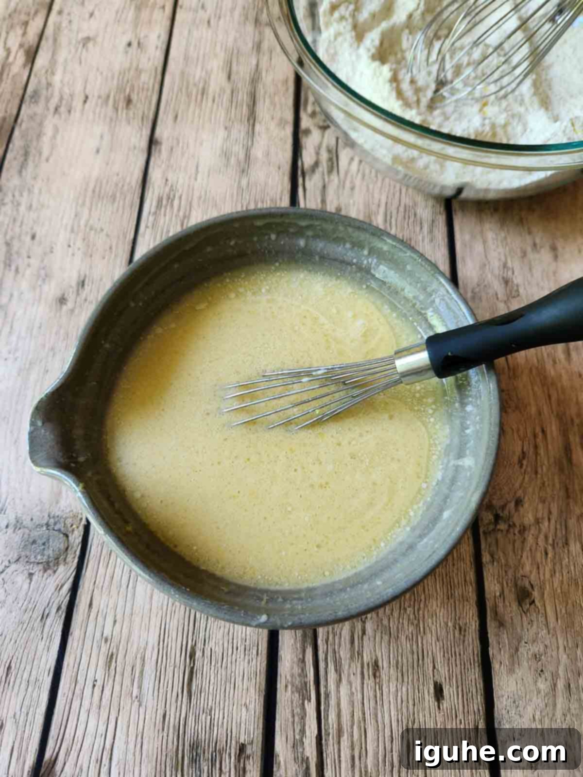 Zesty Lemon Poppy Seed Gems 4 Smooth liquid muffin batter fills a clear mixing bowl, ready for the final dry ingredient incorporation, promising tender, fluffy results.