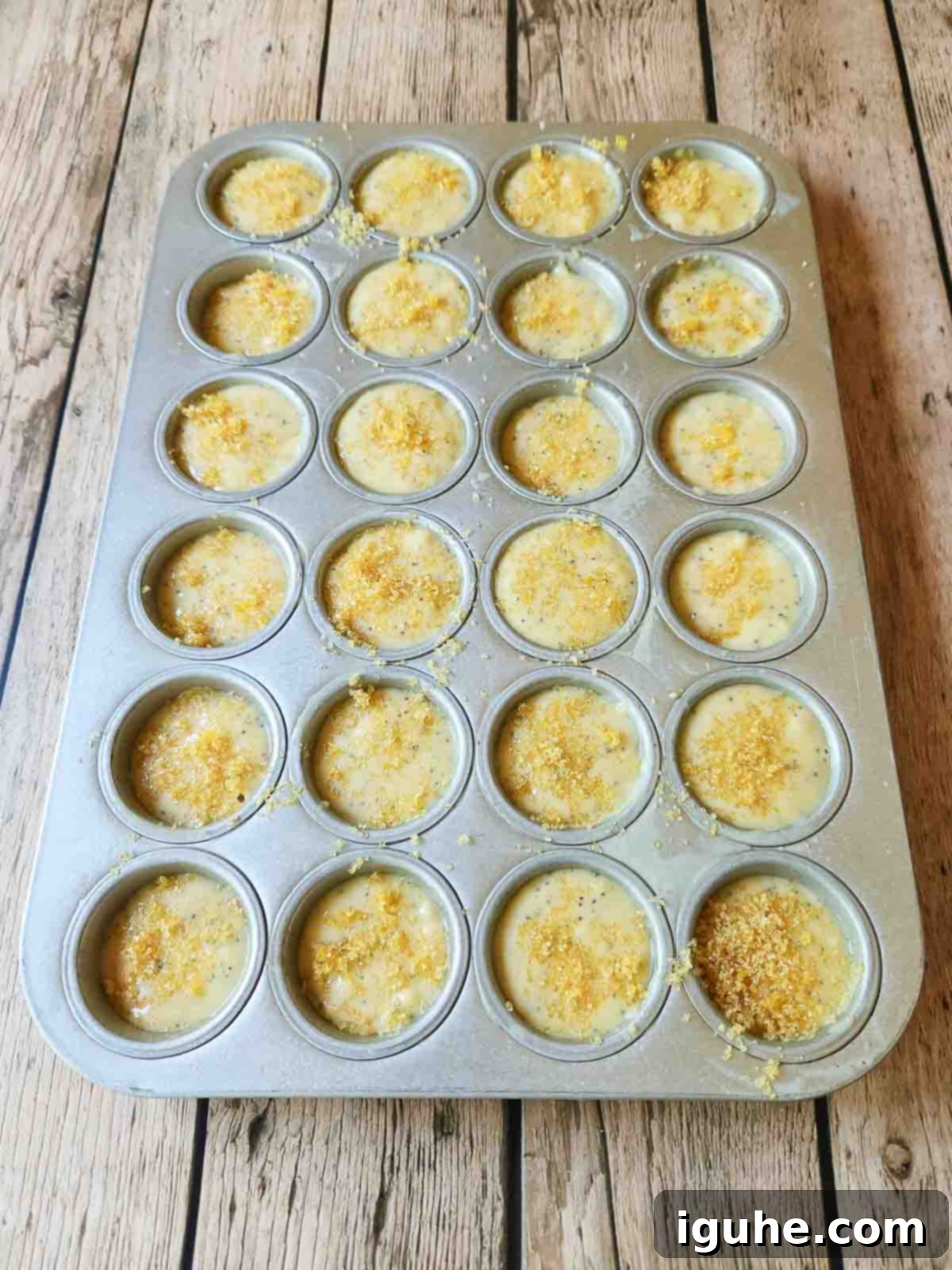 Zesty Lemon Poppy Seed Gems 6 Lush muffin batter perfectly fills a 24-cup mini muffin tin, ready to be baked into golden, bite-sized lemon poppy seed delights.