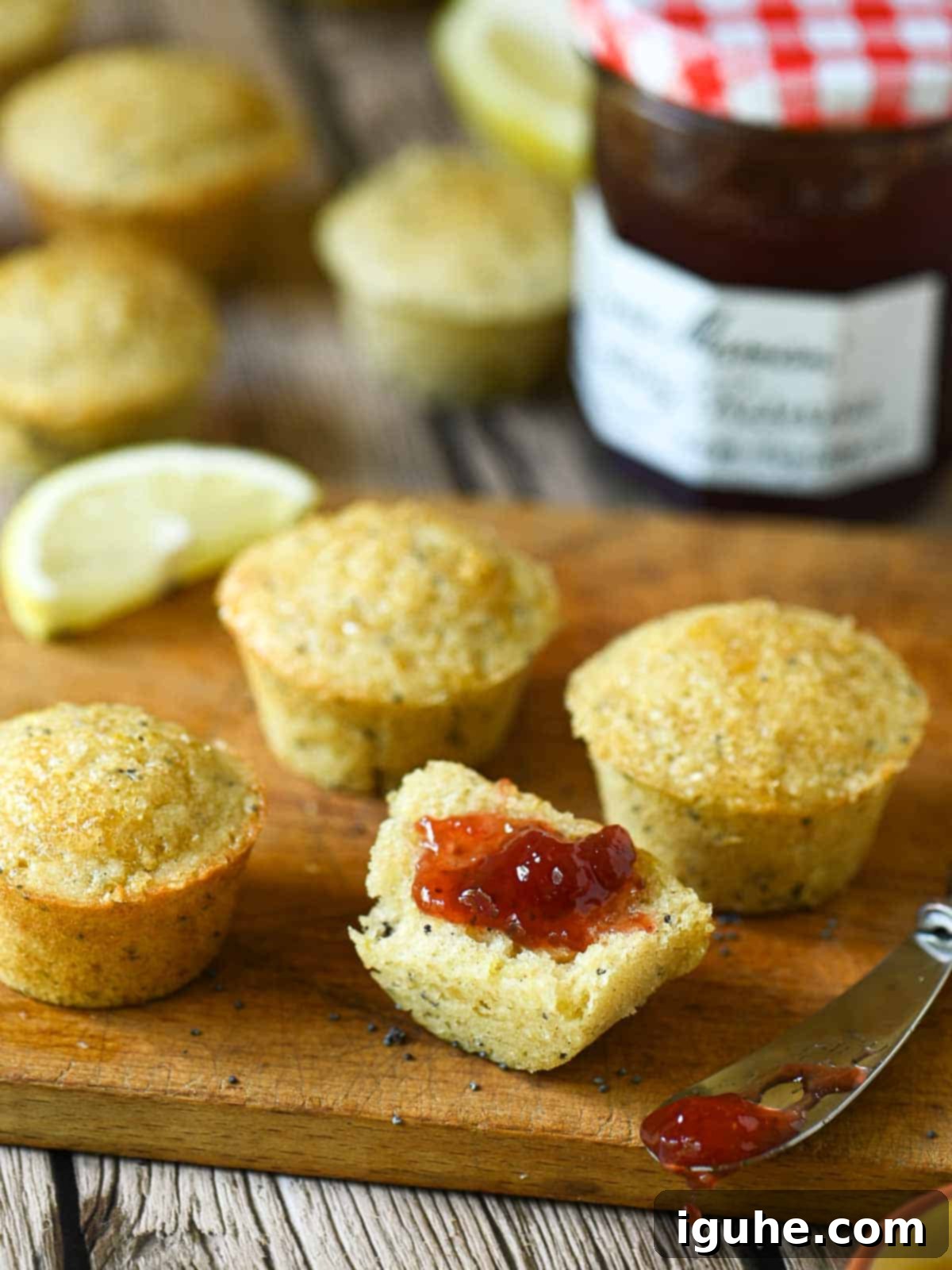 Zesty Lemon Poppy Seed Gems 8 A close-up view of mini lemon poppy seed muffins, cut open and generously spread with vibrant strawberry jam, creating a sweet and tangy breakfast or snack.