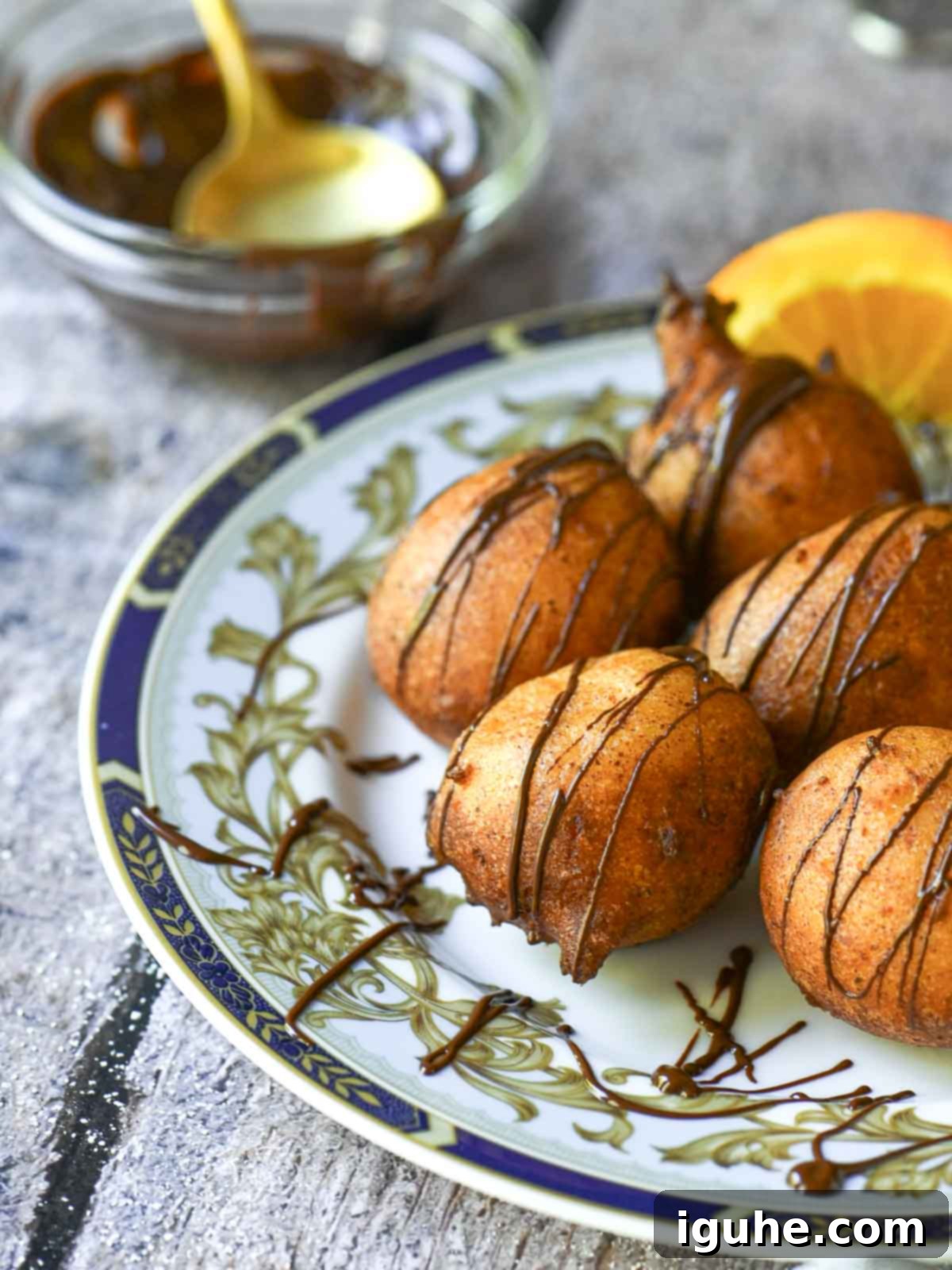 Italian Orange Ricotta Doughnuts 7 Ricotta donuts with chocolate drizzle on a blue plate.
