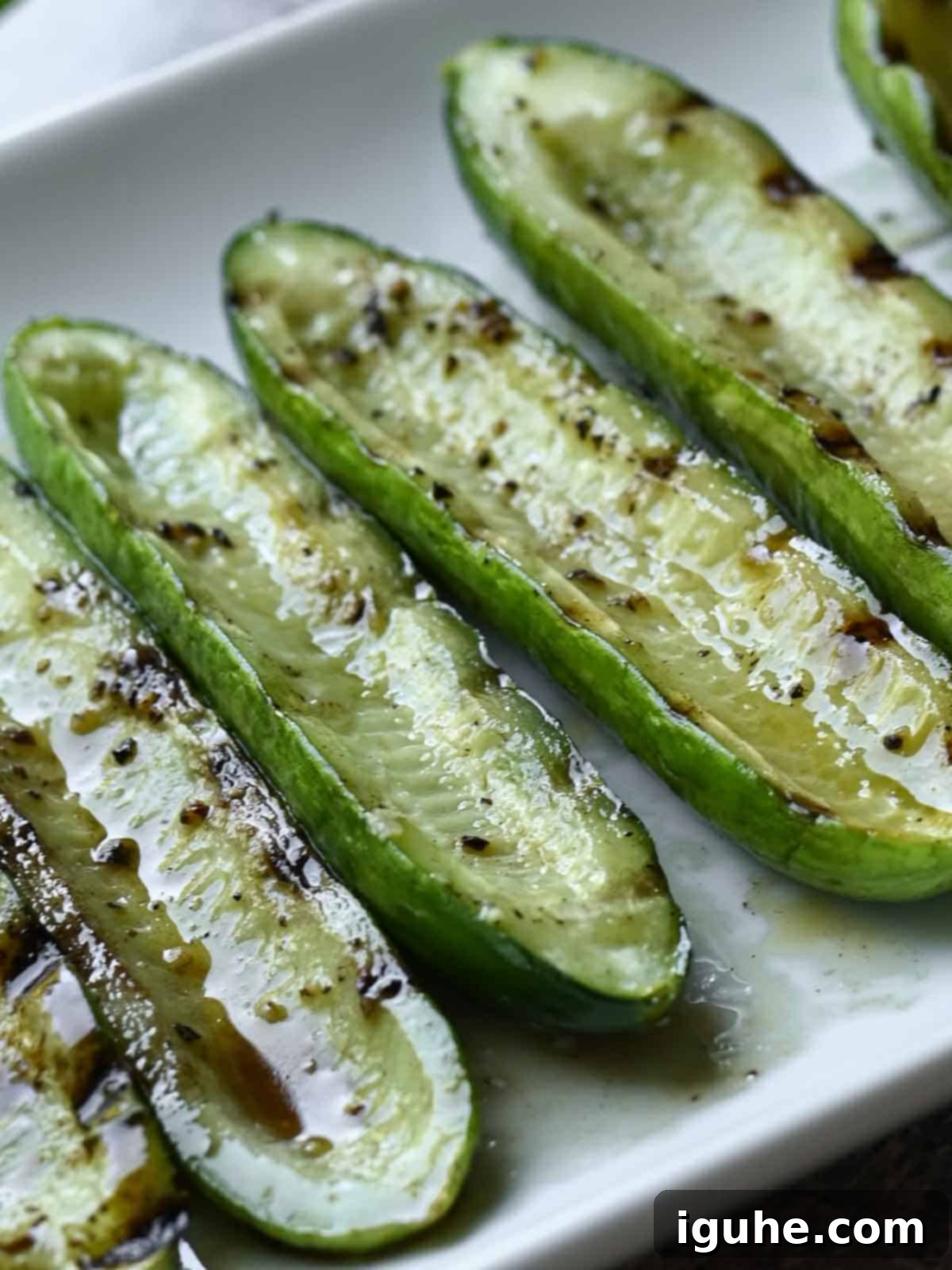 Smoky Grilled Cucumber & Tangy Tzatziki Toast 3 Close-up view of smoky grilled cucumber slices arranged on a pristine white plate, garnished with fresh herbs.