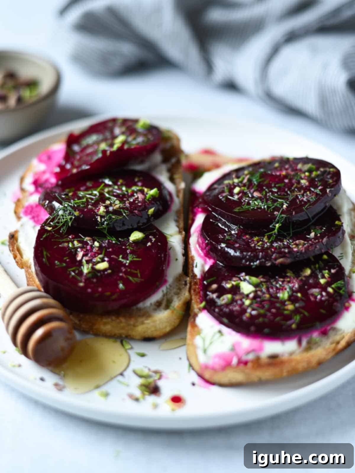 Crimson Beet Toast with Herbed Creme Fraiche 6 Two slices of beet toast on a white plate with a honey drizzle and fresh dill.
