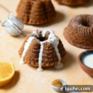 Delightful Mace Spiced Bundt Bites 9 Mini mace bundt cake with white glaze on an orange surface.