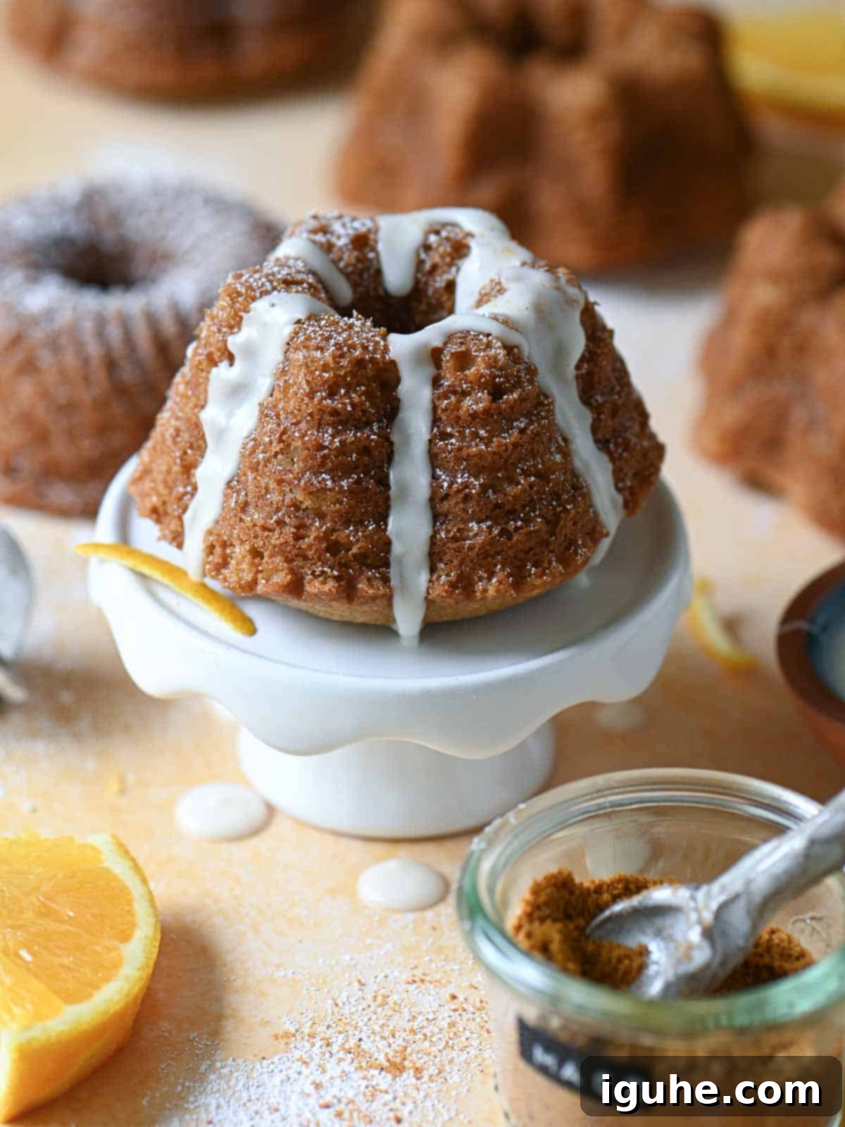 Delightful Mace Spiced Bundt Bites 6 A mini glazed bundt cake on a small white cake pedestal.