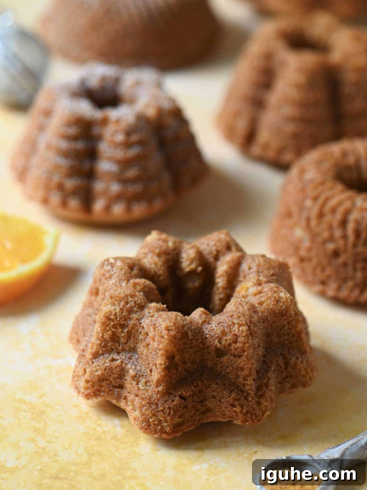 Delightful Mace Spiced Bundt Bites 7 Close-up of mini bundt cakes on an orange surface.