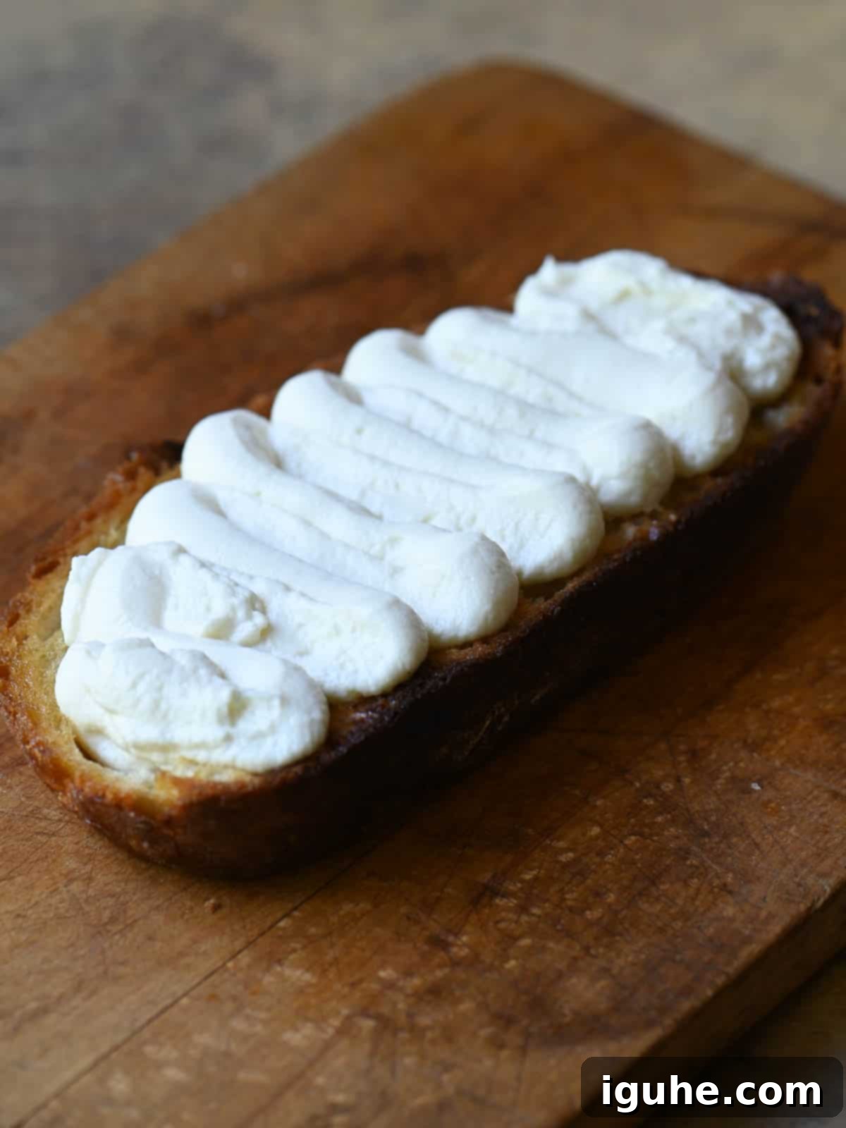 Creamy Ricotta Apple Toast with Sage-Kissed Honey 5 Toasted bread slices spread with creamy ricotta cheese on a wooden cutting board.