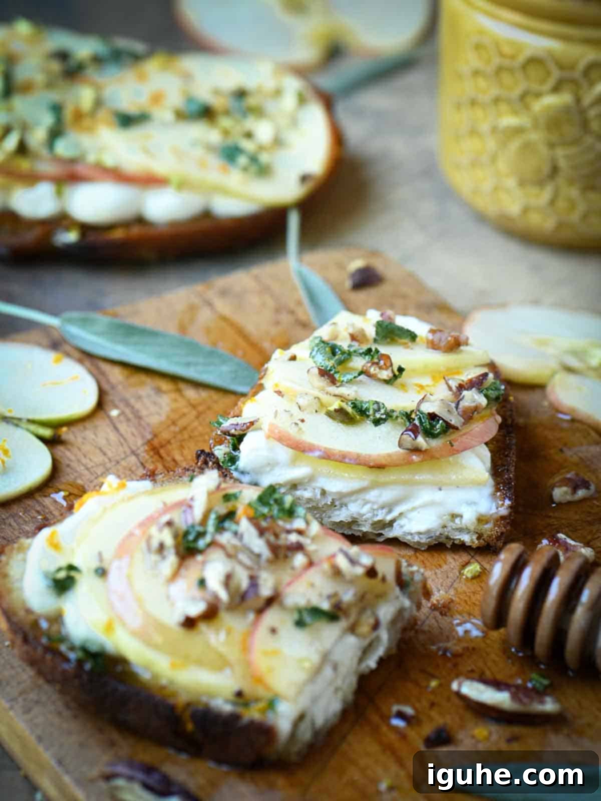 Creamy Ricotta Apple Toast with Sage-Kissed Honey 8 Apple toast sliced diagonally on a cutting board, with fresh sage leaves and a honey drizzle visible.