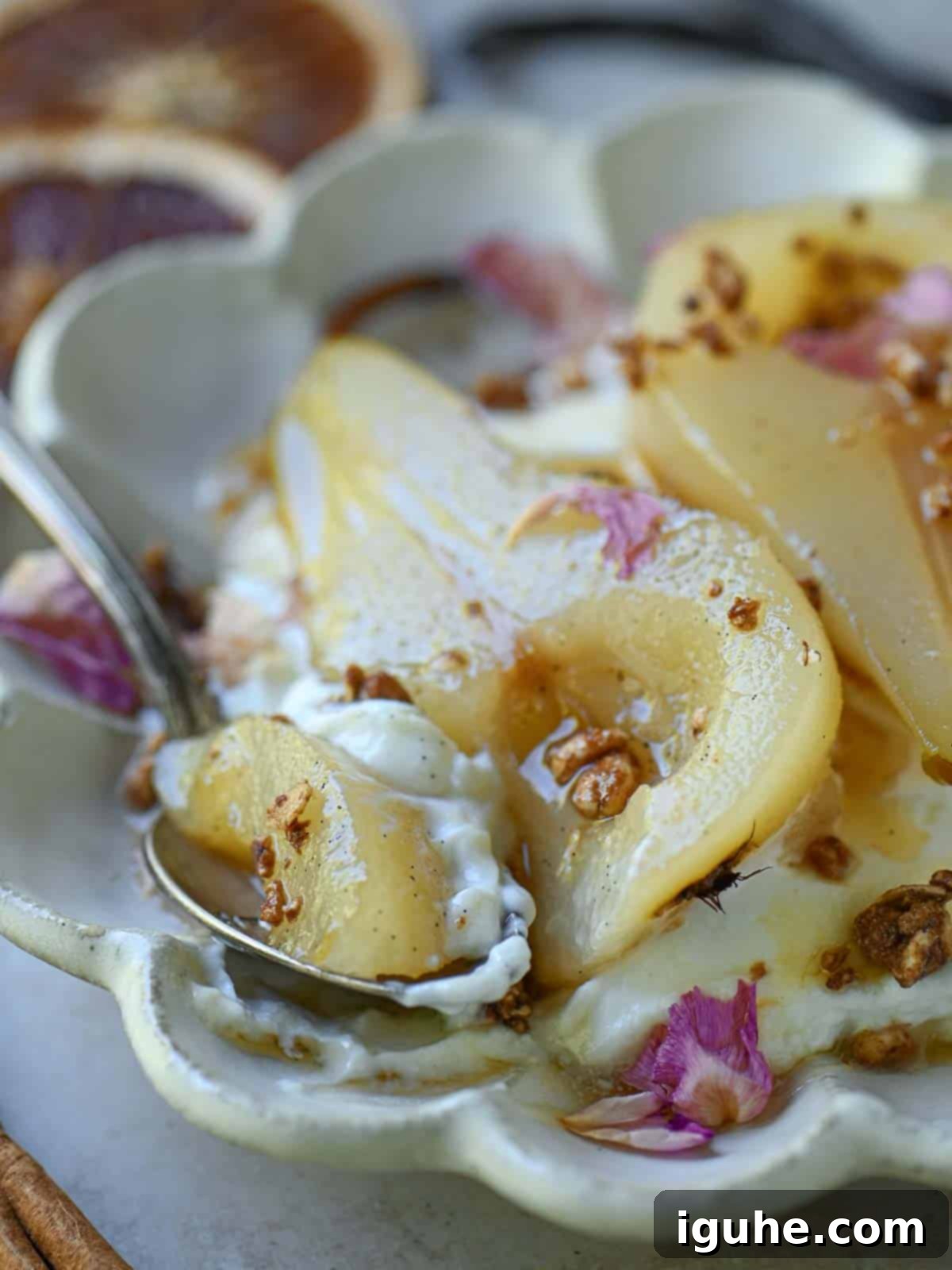 Velvet Vanilla Pears with Creamy Yogurt 7 Close up of poached pears with a spoon on the right in a beige plate.