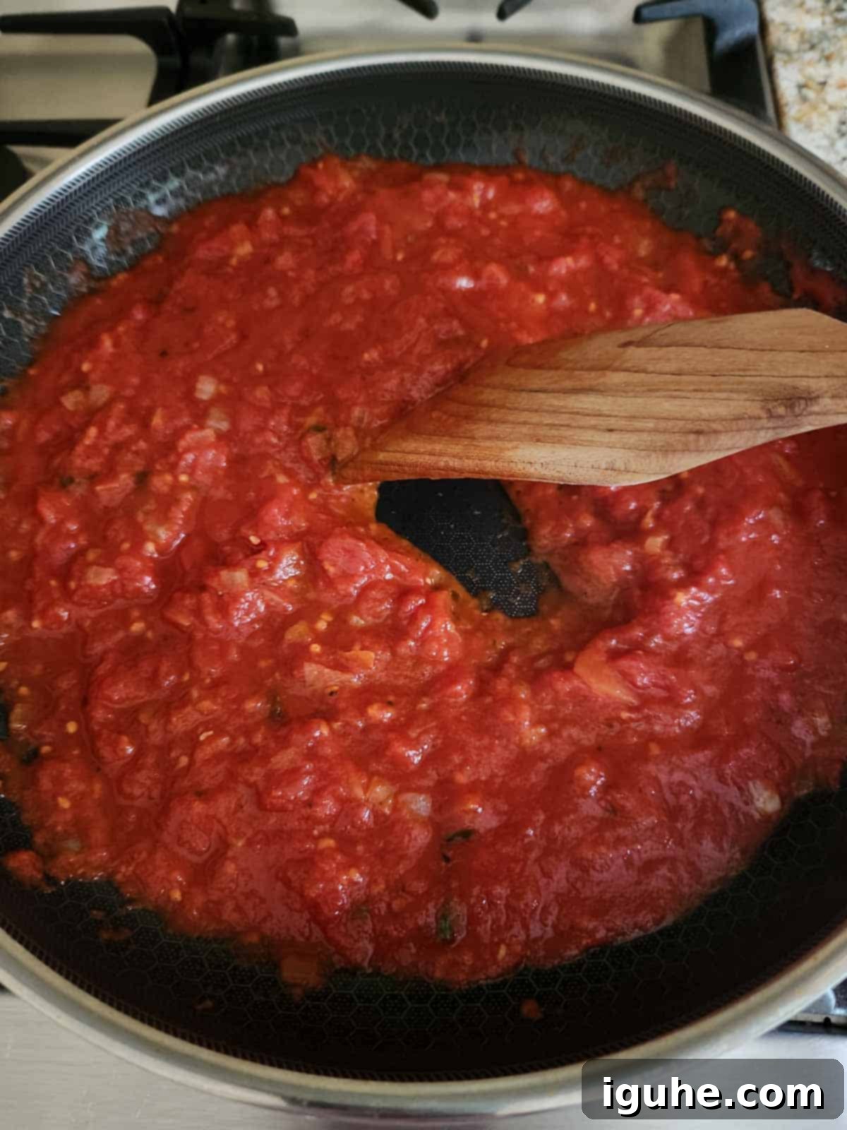 Domates Alevinde Yumurtalar 7 Step 4: Testing the thickness of the tomato sauce with a spoon to ensure it's ready for eggs.