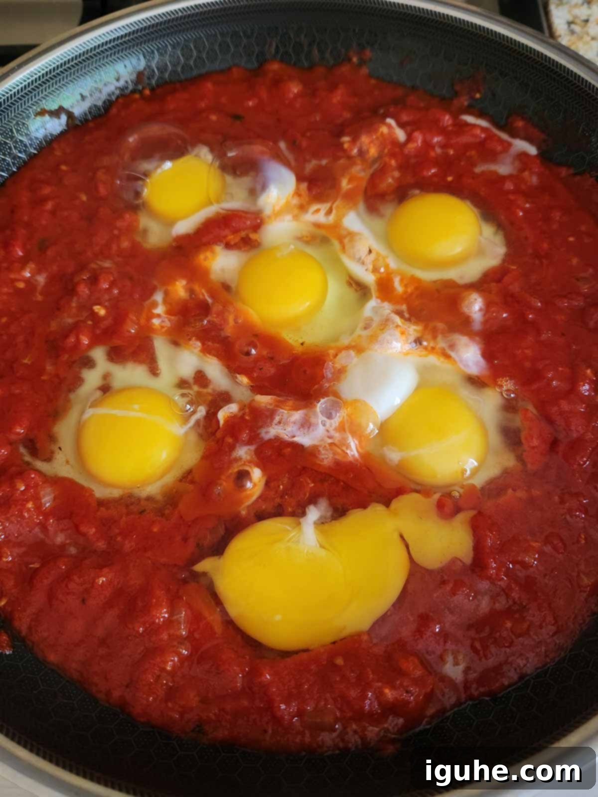 Domates Alevinde Yumurtalar 8 Step 5: Making wells in the thickened tomato sauce and gently placing eggs into them.