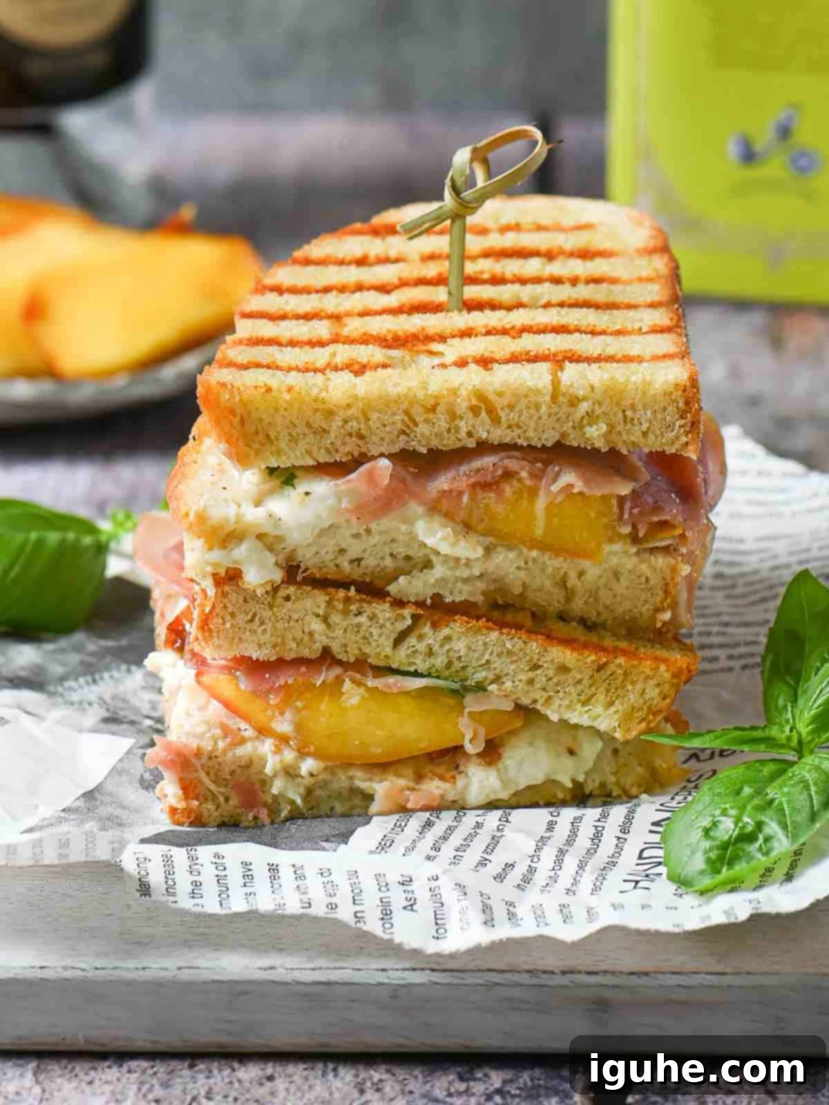 Stacked peach panini sandwiches on a grey board, showcasing golden bread and vibrant fillings.