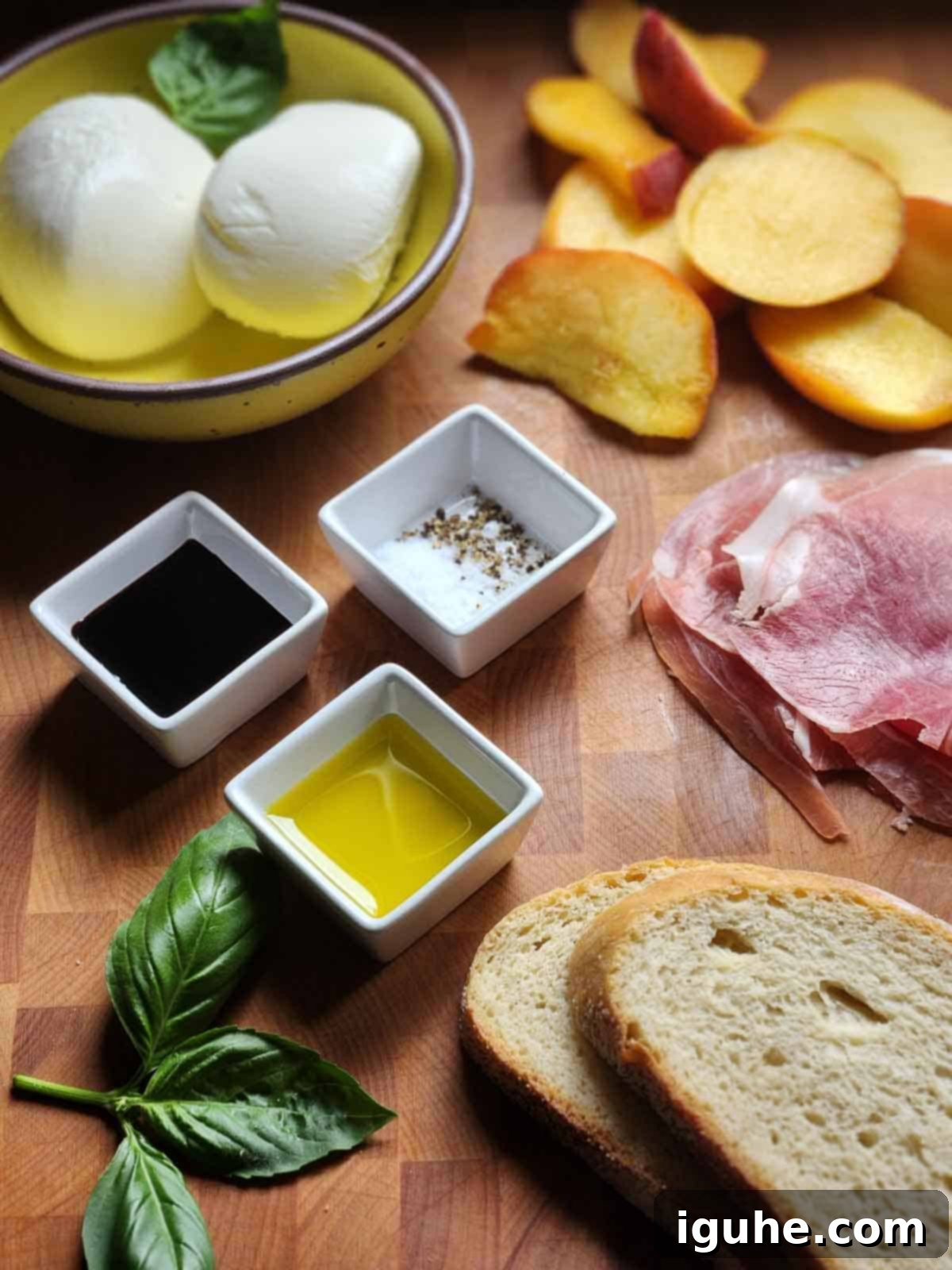 Sweet and Savory Peach Prosciutto Burrata Panini 3 A vibrant selection of ingredients for a peach panini laid out on a cutting board, including fresh peaches, burrata, prosciutto, and basil.