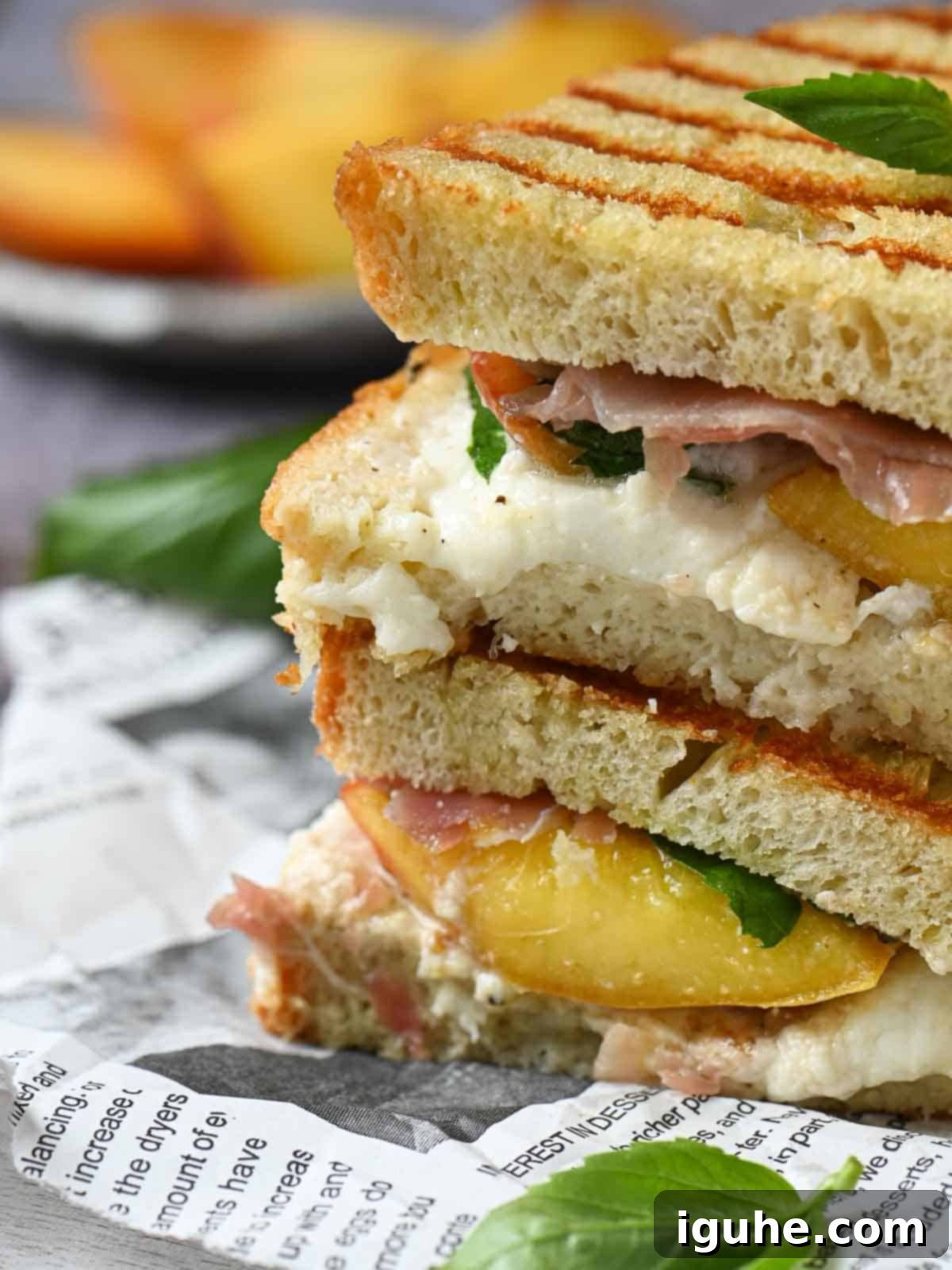 Sweet and Savory Peach Prosciutto Burrata Panini 6 A close-up view of a peach panini, revealing its melted burrata, fresh basil, and savory prosciutto filling.