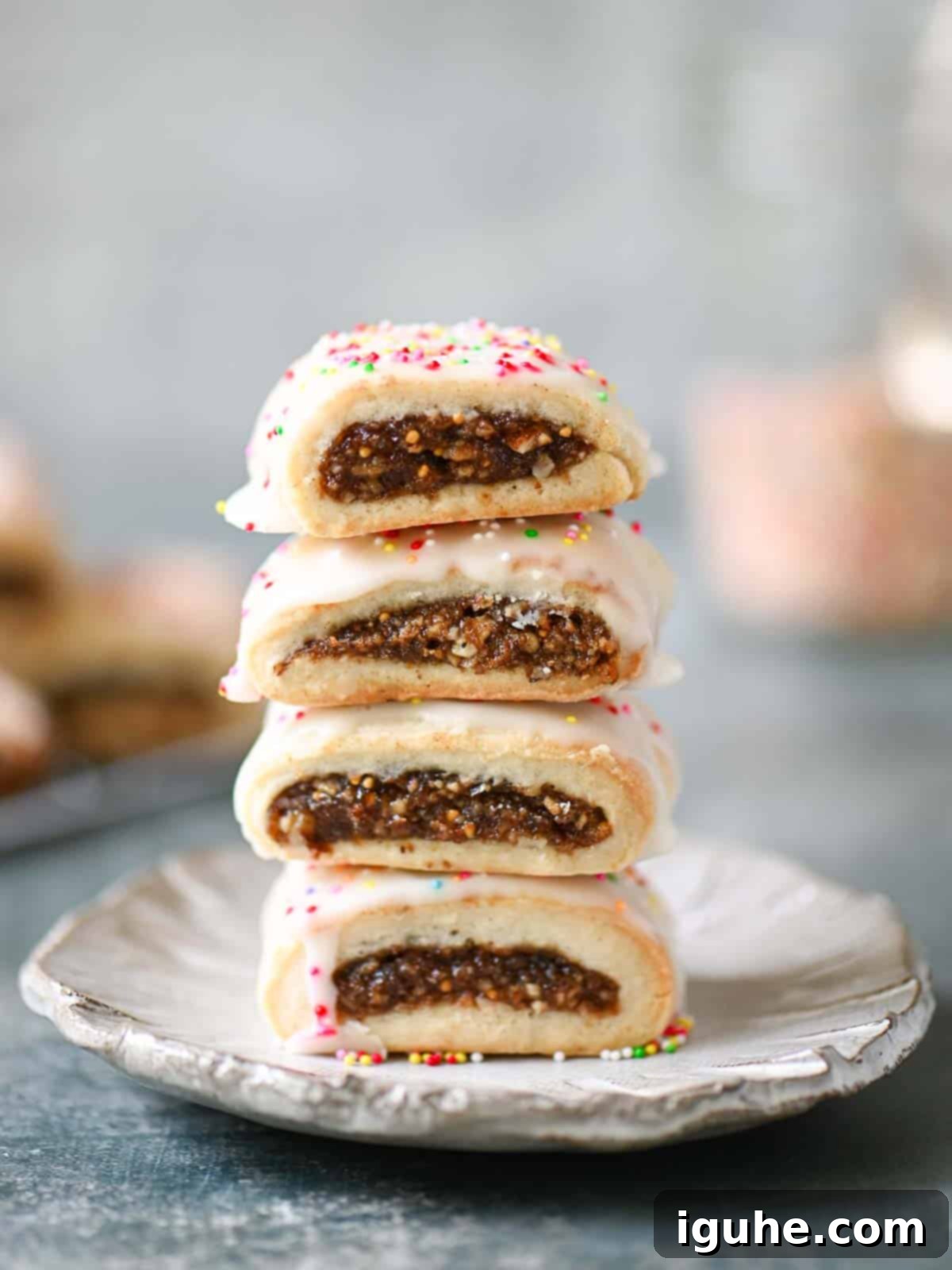 Sicilian Cuccidati Festive Fig Cookies 3 A stack of four perfectly iced cuccidati on a grey plate, ready to be enjoyed.