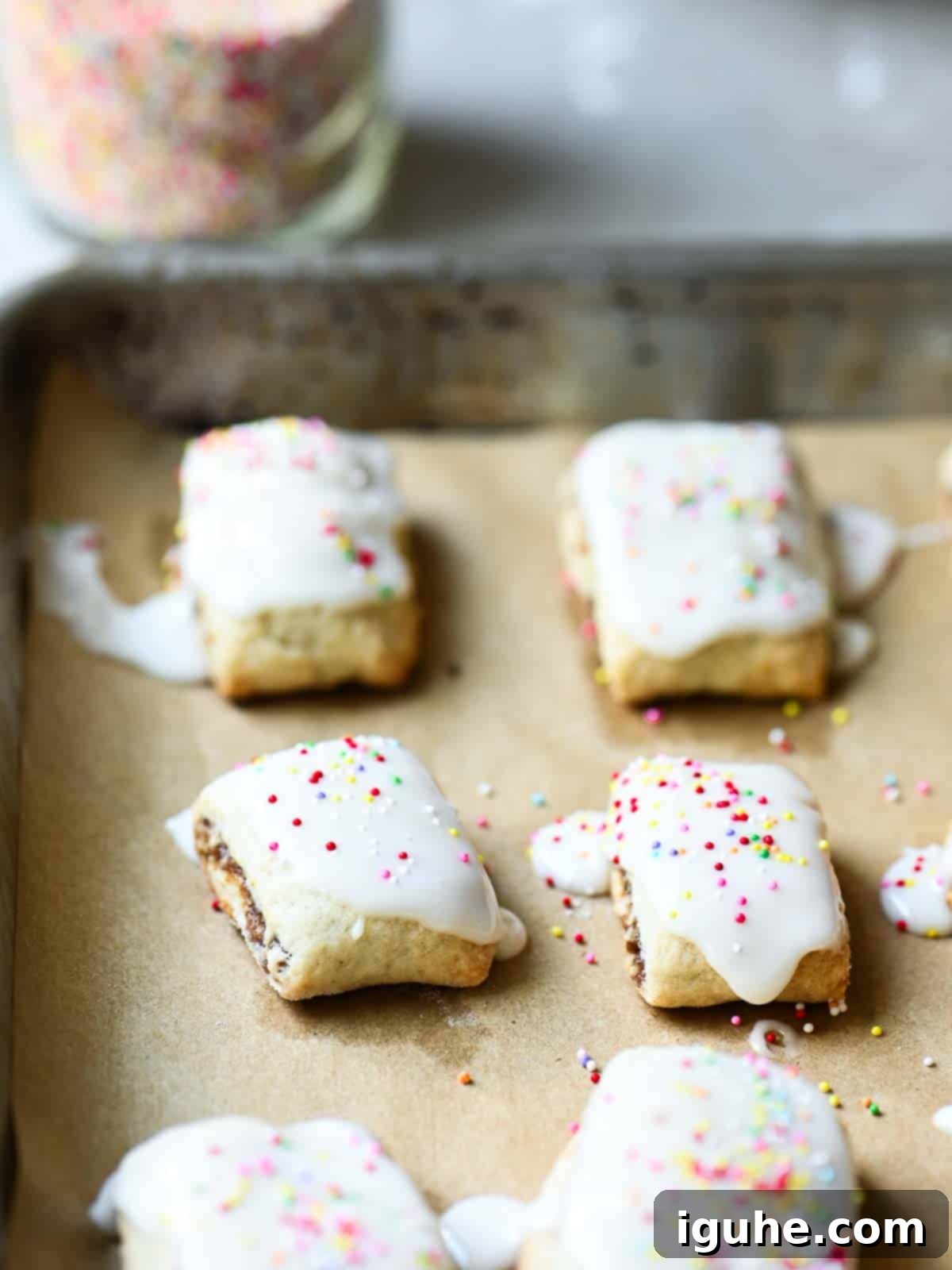 Sicilian Cuccidati Festive Fig Cookies 9 Italian fig cookies on parchment paper, adorned with vibrant colorful sprinkles, showcasing their festive appeal.
