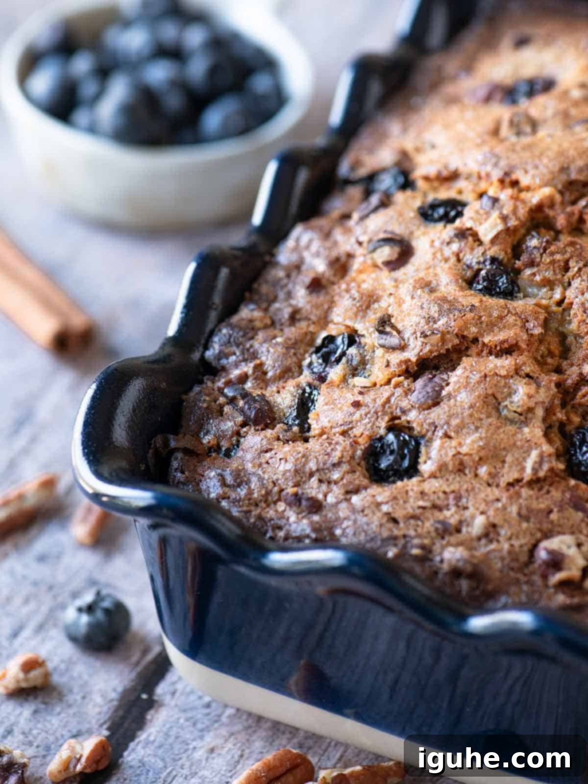 Close-up of blueberry banana bread in a blue ruffled loaf pan, showcasing its golden crust and blueberry swirls.