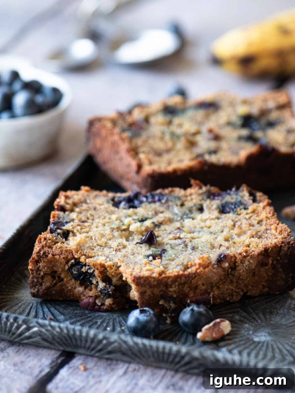 Moist Blueberry Banana Nut Bread 5 Two slices of banana blueberry bread on a metal pan, showing the moist interior and distribution of blueberries.