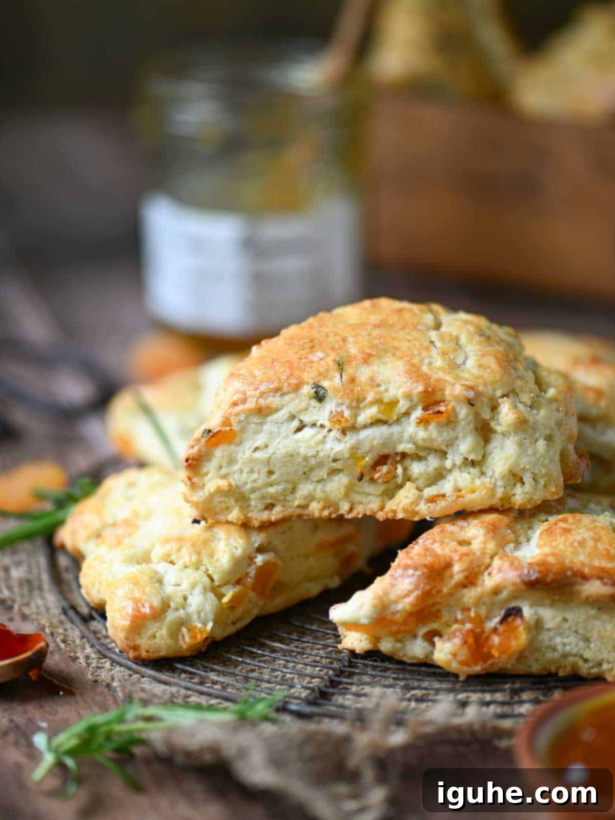 Apricot and rosemary scones on a wire rack on a wood surface, freshly baked and golden.