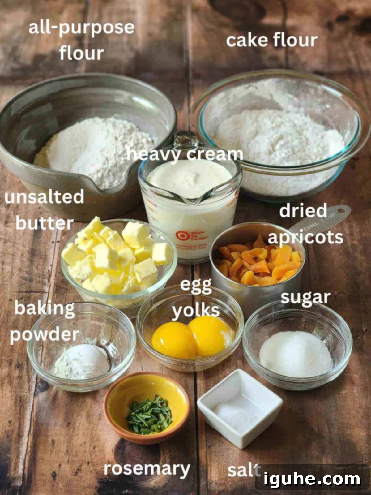 Sunshine Apricot Rosemary Scones 3 Various ingredients for rosemary scones, including flour, sugar, butter, and apricots, laid out in bowls on a rustic wood surface.