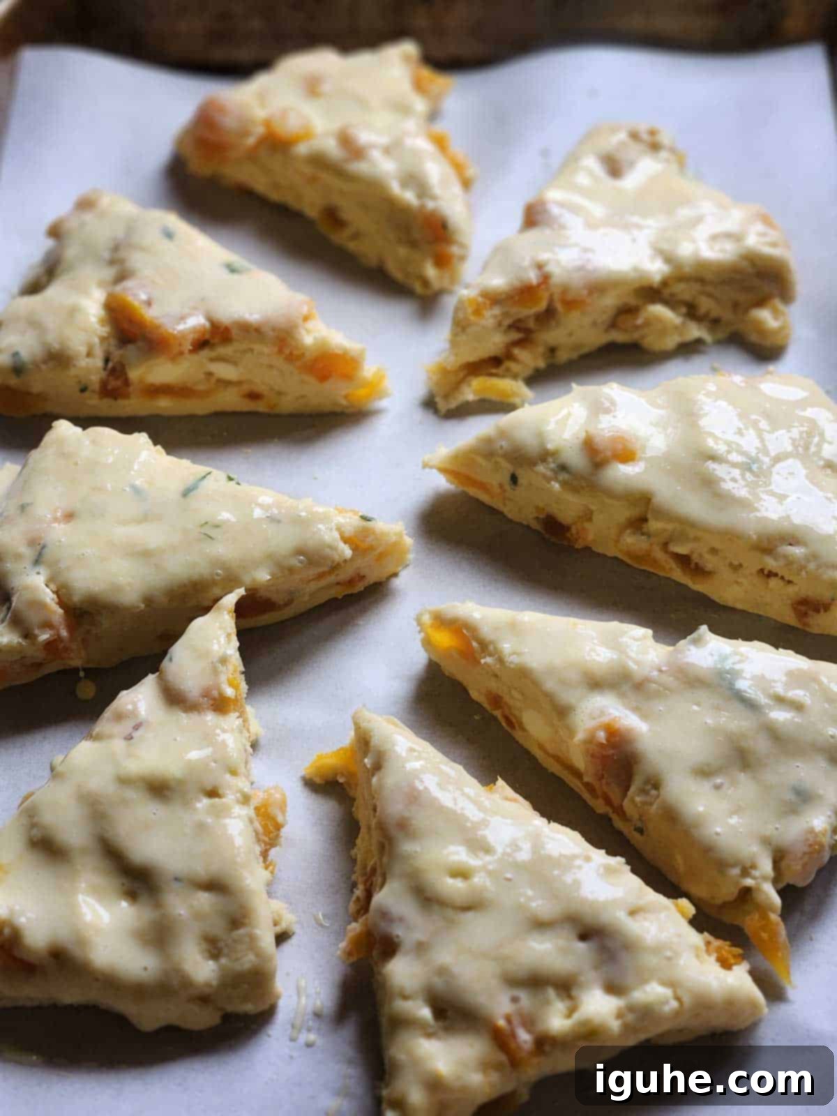 Sunshine Apricot Rosemary Scones 5 Scone wedges arranged on a baking sheet, brushed with an egg wash, ready for baking.