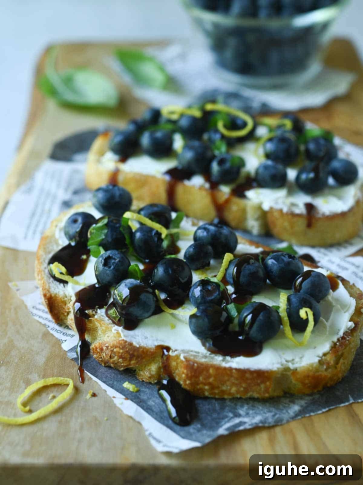 Blueberry Bliss Toast 7 Two blueberry toasts on a wood board with date syrup drizzled on them.