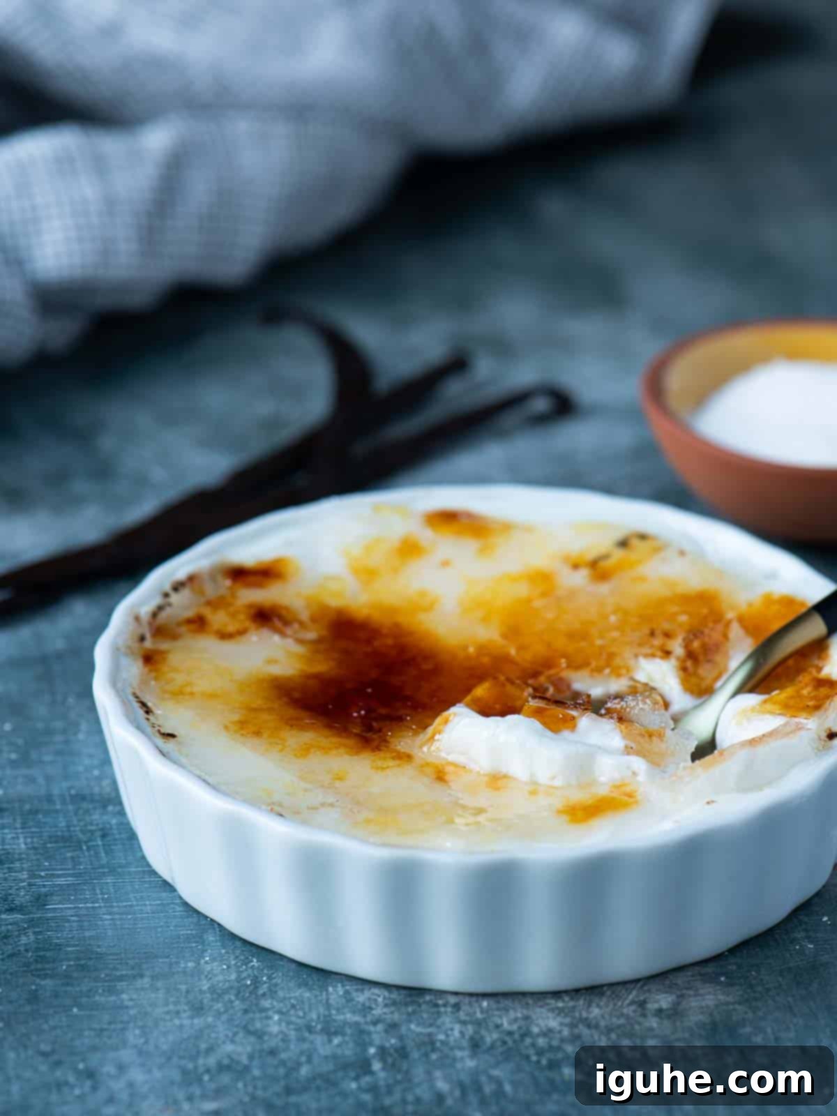 Effortless Vanilla Yogurt Brulee 7 Vanilla yogurt brulee in a white ramekin with a spoon, ready to eat.