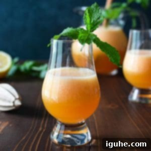 Refreshing Cantaloupe Lime Agua Fresca 3 Eye level view of canteloupe lime agua fresca on a wooden background with mint in the glass