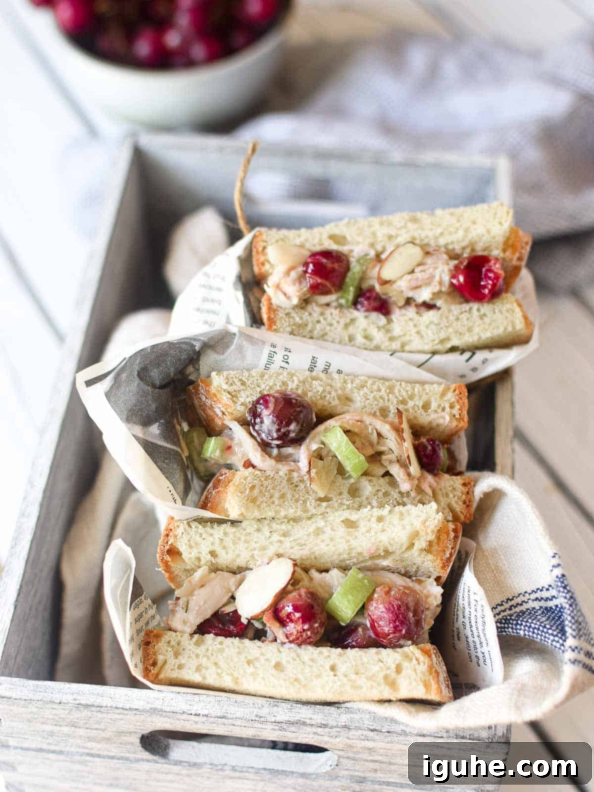 Roasted Grape Rotisserie Chicken Salad 2 Overhead view of chicken salad with roasted grape sandwiches wrapped in deli paper placed in a grey box