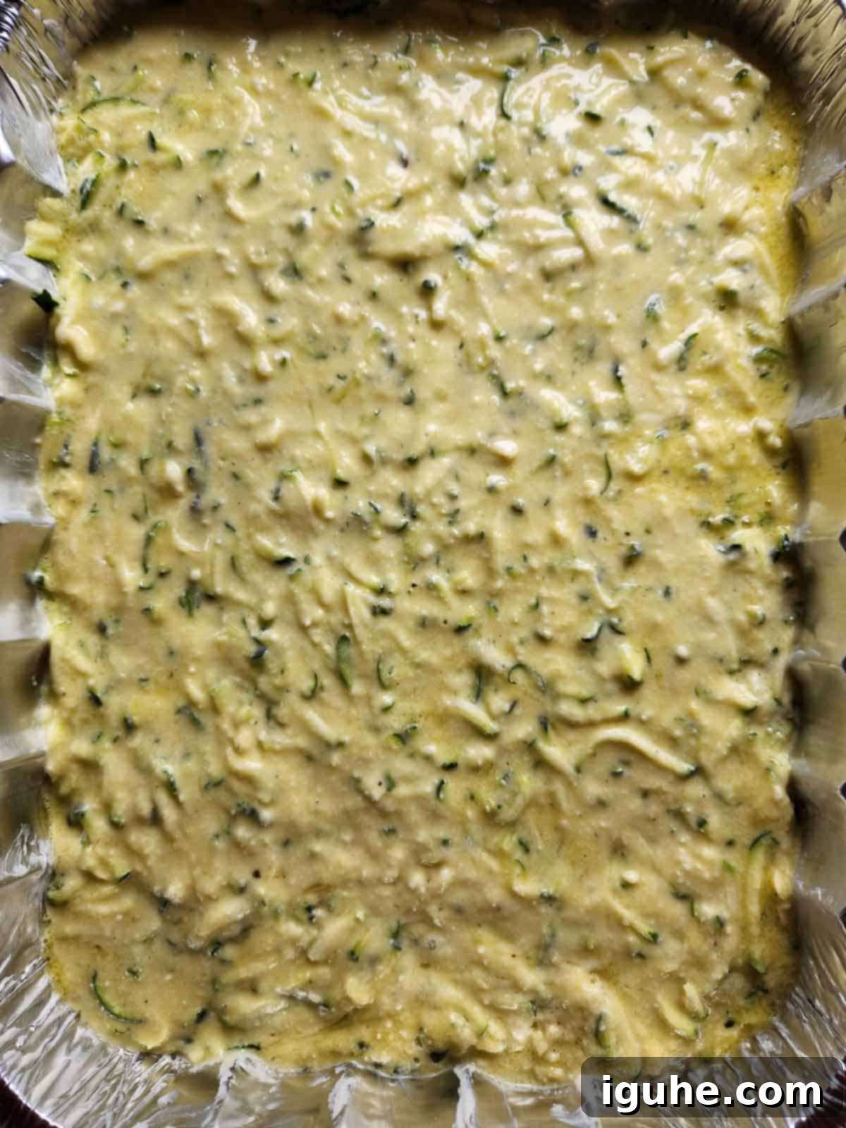 Naked Zucchini Quiche 6 Smooth batter for crustless zucchini pie poured into a metal baking pan, ready for the oven to bake into a golden delight.