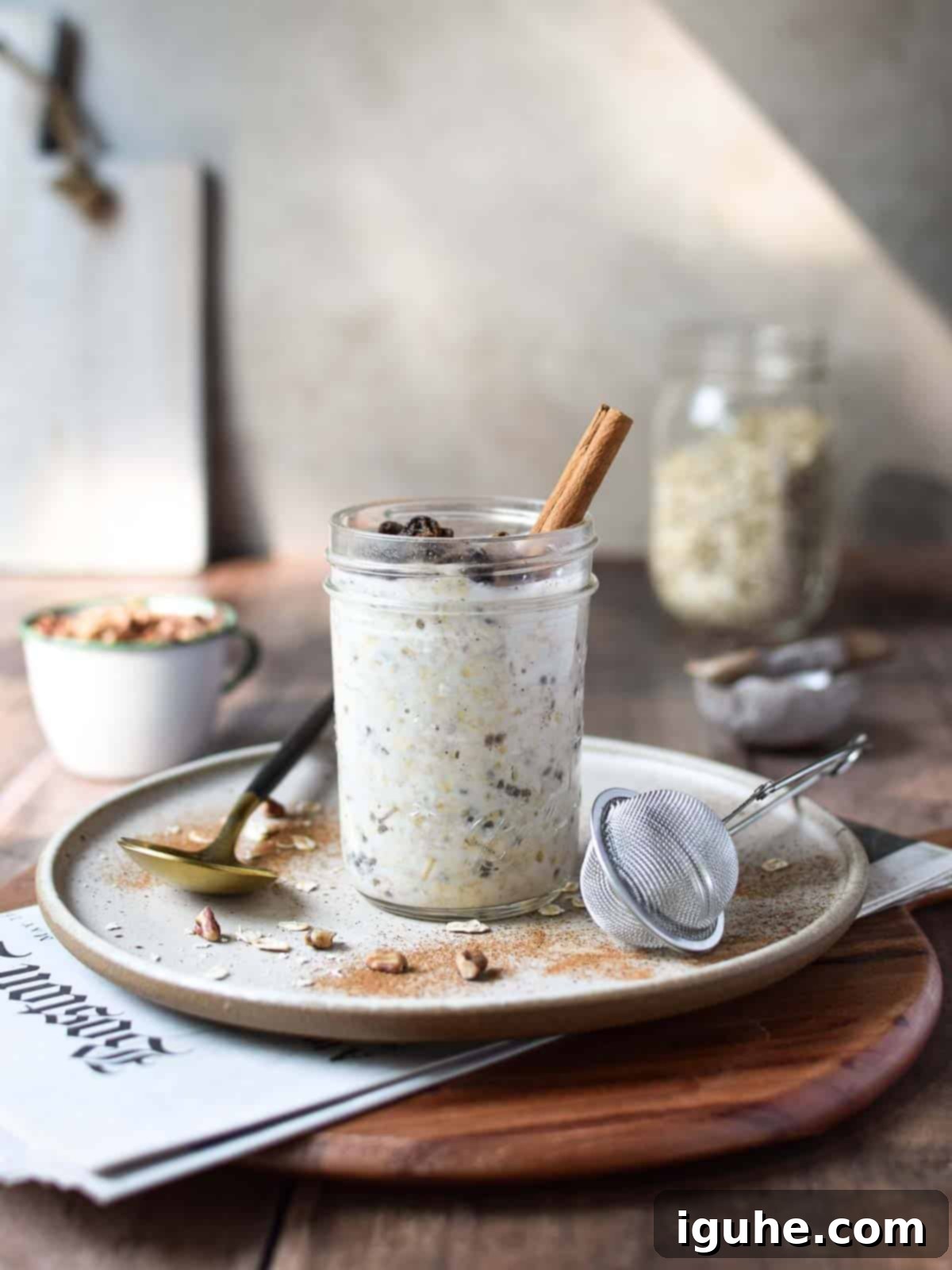 Creamy Maple Raisin Overnight Oats 2 Eye-level view of overnight oats in a jar on a wood surface with the Sunday paper showing.