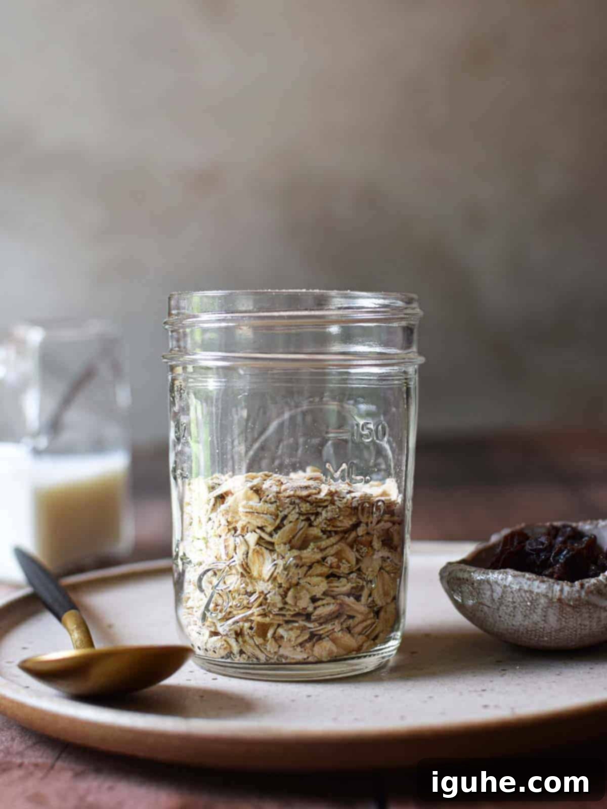 Creamy Maple Raisin Overnight Oats 4 Oats in a jar on a brown plate.