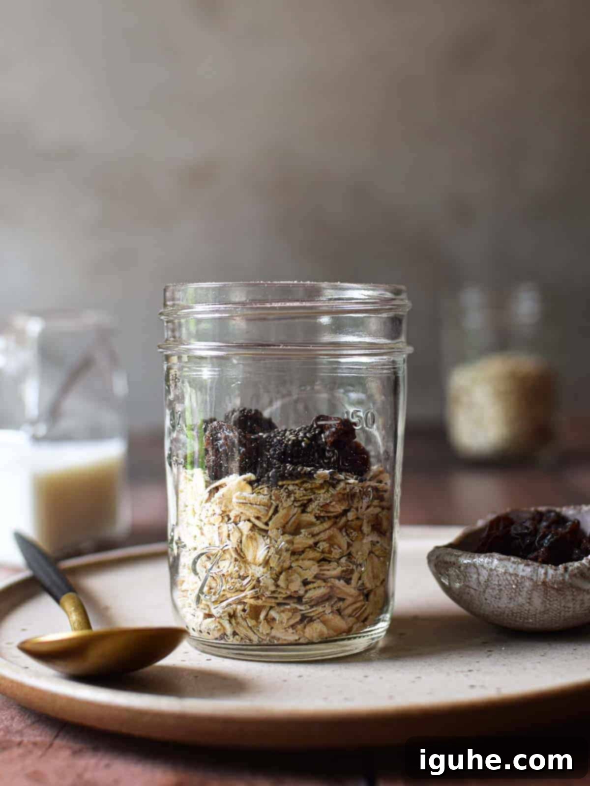 Creamy Maple Raisin Overnight Oats 5 Oats and raisins in a clear jar on a beige plate.