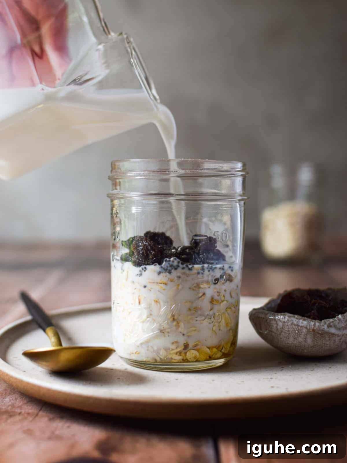 Creamy Maple Raisin Overnight Oats 6 Milk is poured into a Mason jar to prepare overnight oats.