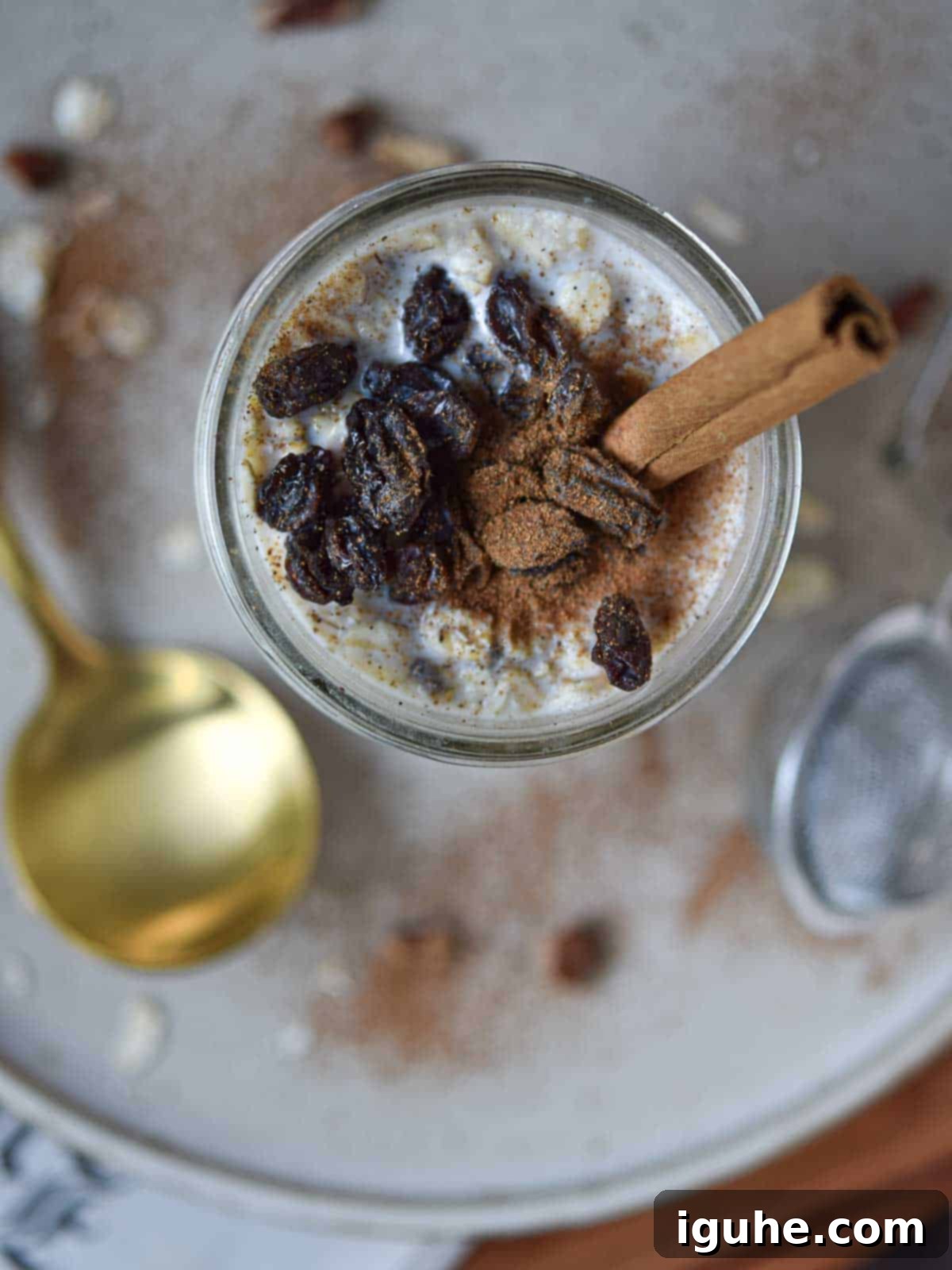 Creamy Maple Raisin Overnight Oats 9 Overhead view of overnight oats in a jar with raisins and a cinnamon stick.