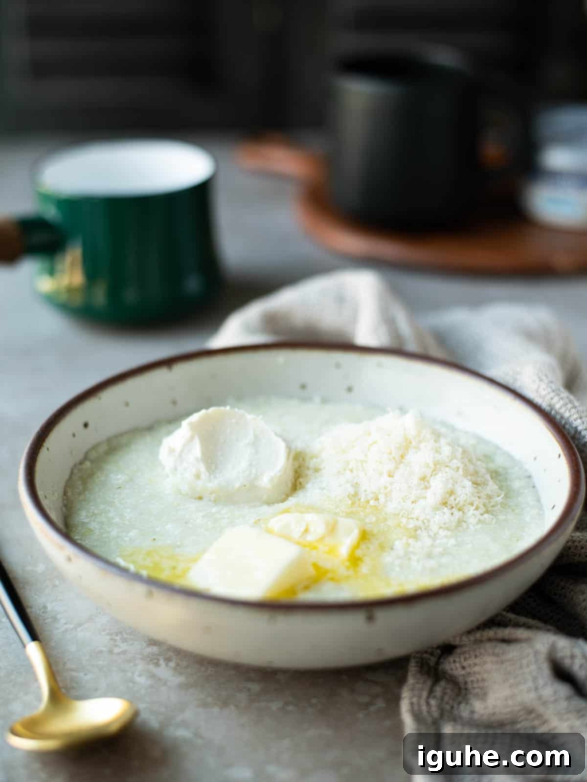 Creamy Everything Bagel Grits 4 Grits with cream cheese, butter and parmesan in a beige bowl, ready to be stirred.