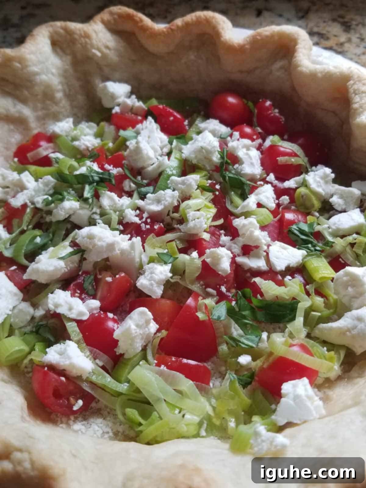 Sun-Kissed Tomato Feta Leek Quiche 7 Par baked pie dough with tomato leeks and feta prepared for oven