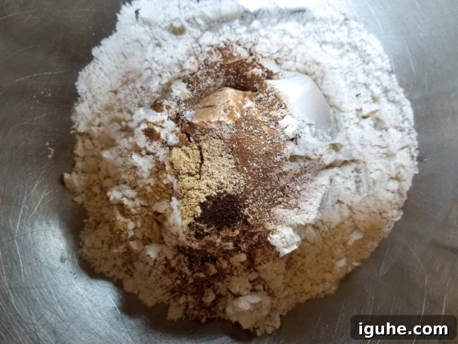 Pumpkin Spice Belgian Waffles 3 A large bowl containing dry ingredients for pumpkin waffles: flour, baking powder, baking soda, salt, and various ground spices, ready to be whisked together.