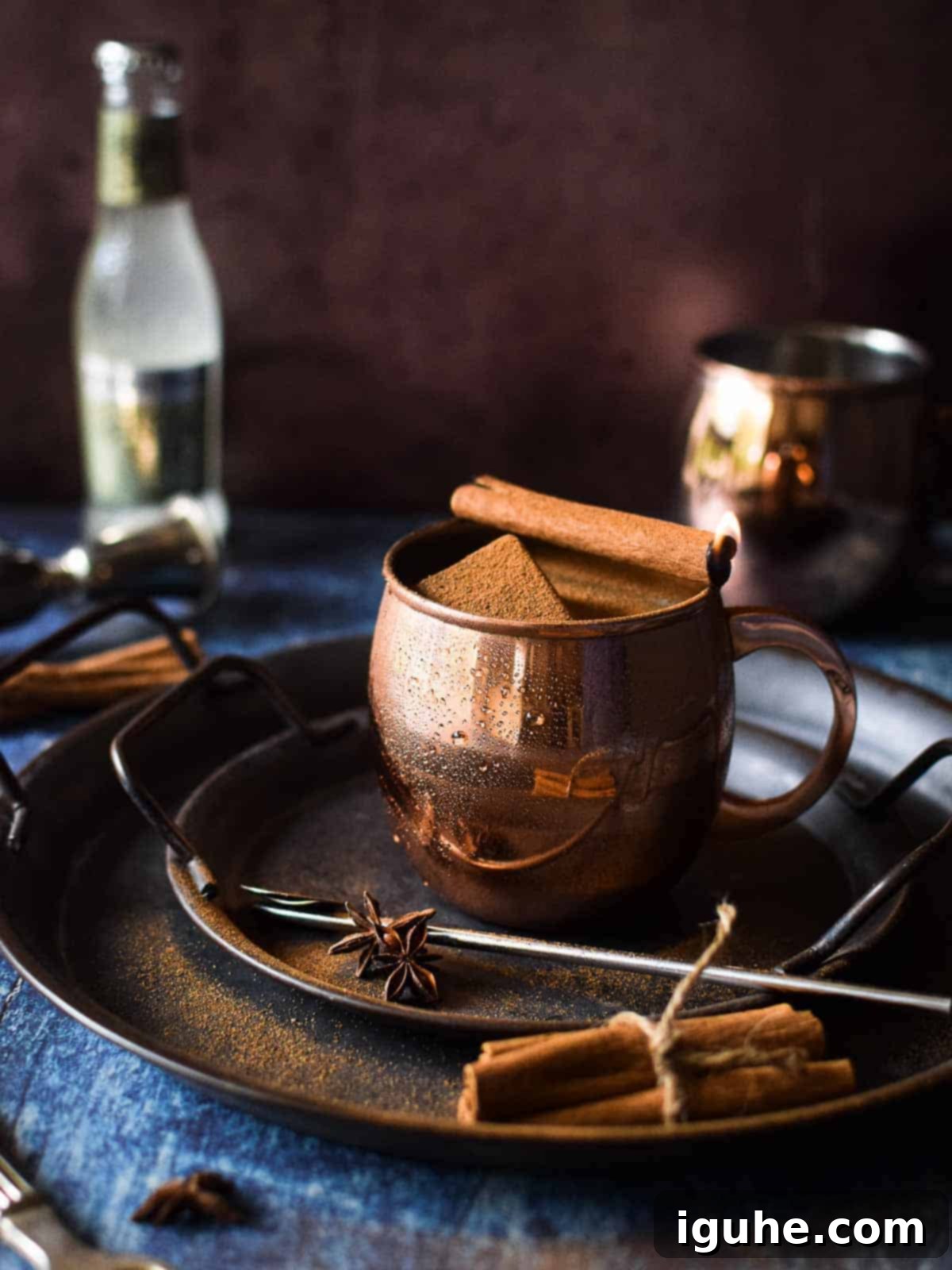 Chai Moscow mule in a copper mug with a cinnamon stick on fire.