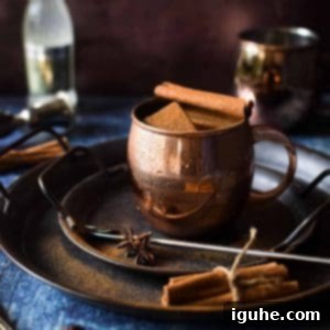 Caramelized Cinnamon Chai Mule 5 Chai Moscow mule in a copper mug with a cinnamon stick on fire.