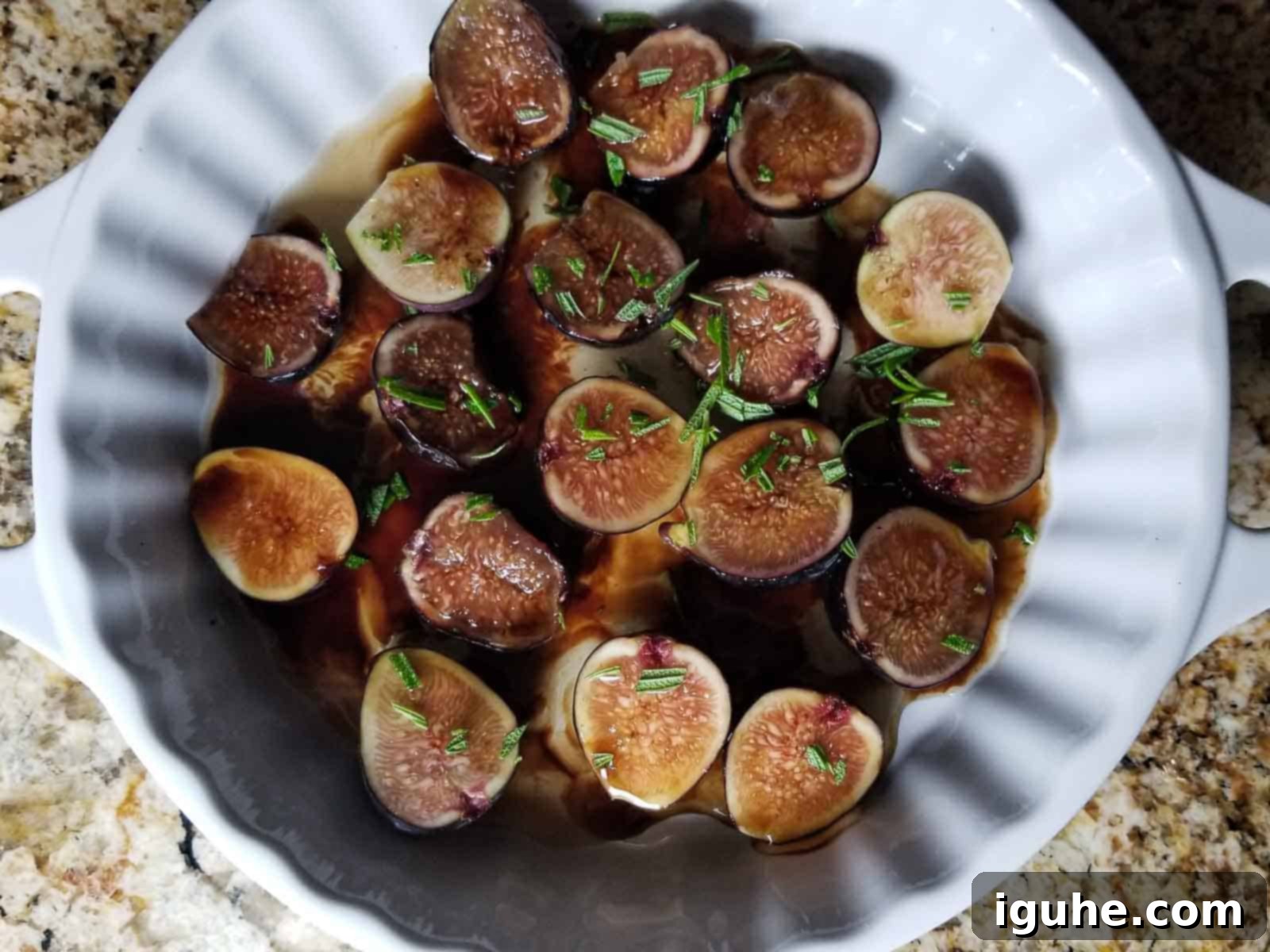 Aromatic Roasted Fig and Rosemary Butter Board 3 Sliced fresh figs marinating in a white bowl with orange liqueur, balsamic, honey, and fresh rosemary sprigs.