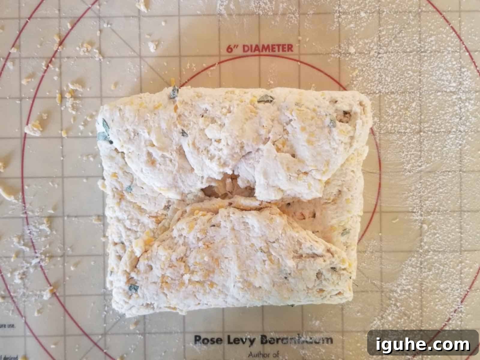 Golden Cheddar Sage Biscuits 7 Process shot of biscuit dough being folded inward on a floured surface to create layers.