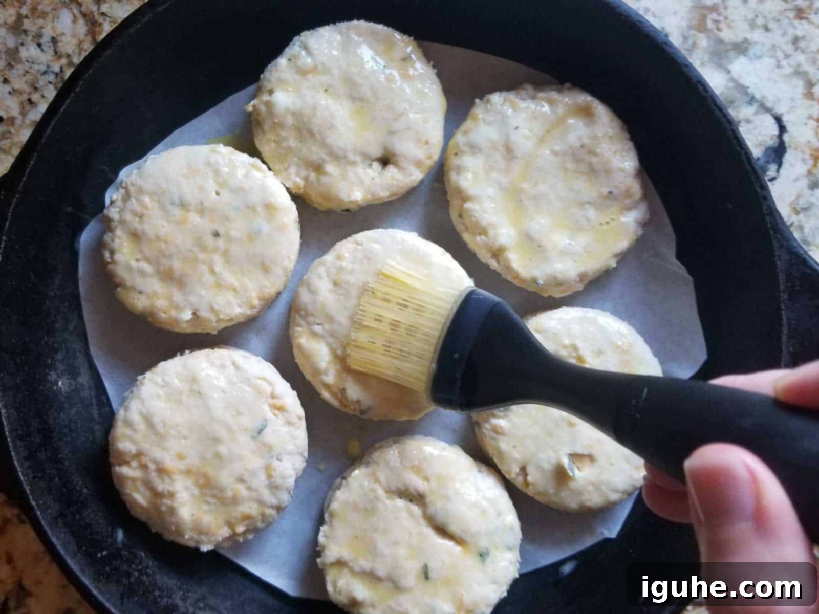 Golden Cheddar Sage Biscuits 9 Cut biscuits brushed with egg wash and placed in a cast iron skillet, ready for baking.