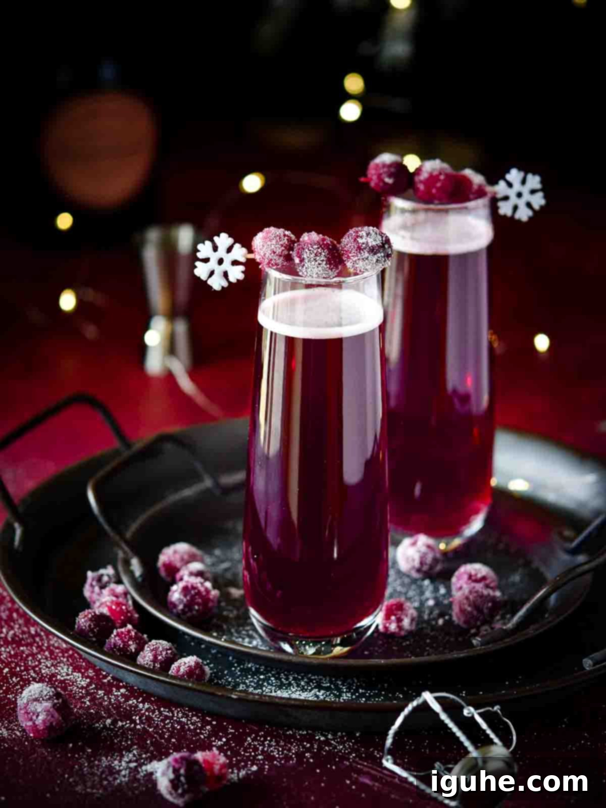 Cranberry mimosas with sugared cranberries on a black tray, ready to be served.