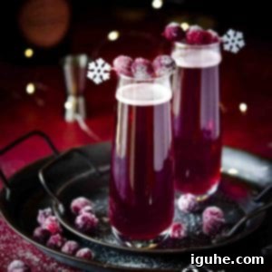 Frosted Cranberry Mimosa 5 Cranberry mimosas with sugared cranberries on a black tray, sparkling and ready to serve.