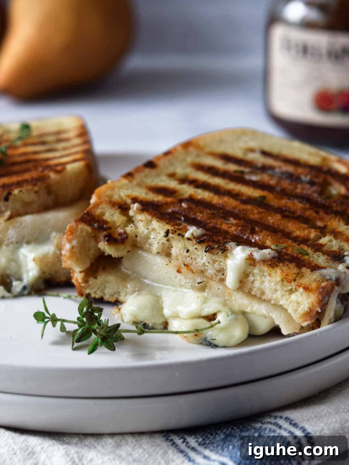 Gorgonzola grilled cheese cut in half on a white plate.