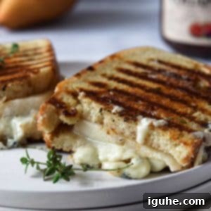 Sweet Pear and Pungent Gorgonzola Grilled Cheese 9 Gorgonzola grilled cheese cut in half on a white plate.
