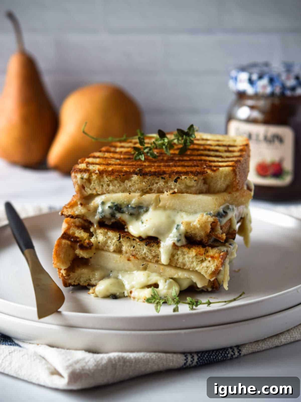 Sweet Pear and Pungent Gorgonzola Grilled Cheese 3 Gorgonzola and pear grilled cheese stacked and melty on a white plate.