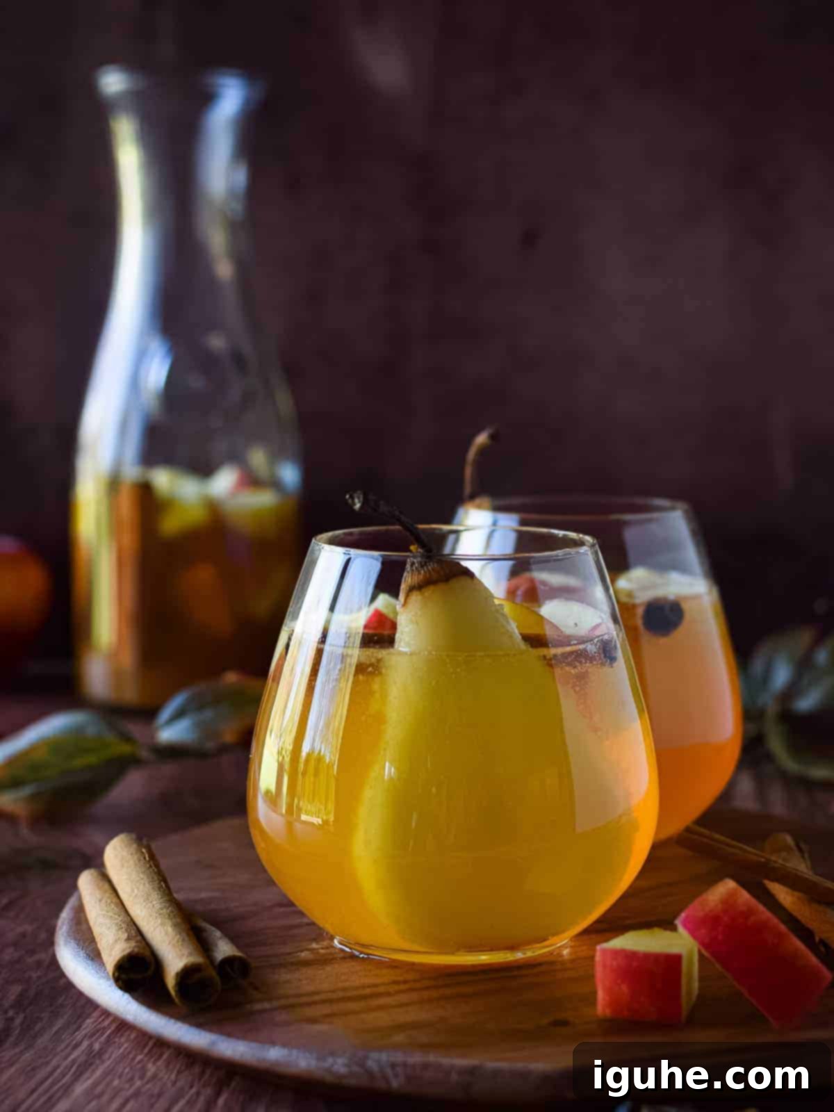 Autumn Orchard White Sangria 3 Apple and pear sangria in a glass on a wooden board, garnished with fruit slices.