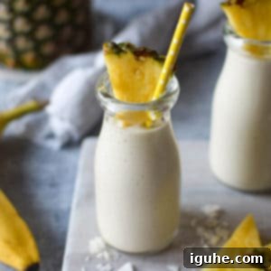 Tropical Banana Pineapple Bliss 5 Close-up of banana and pineapple smoothie in a clear glass with a straw.