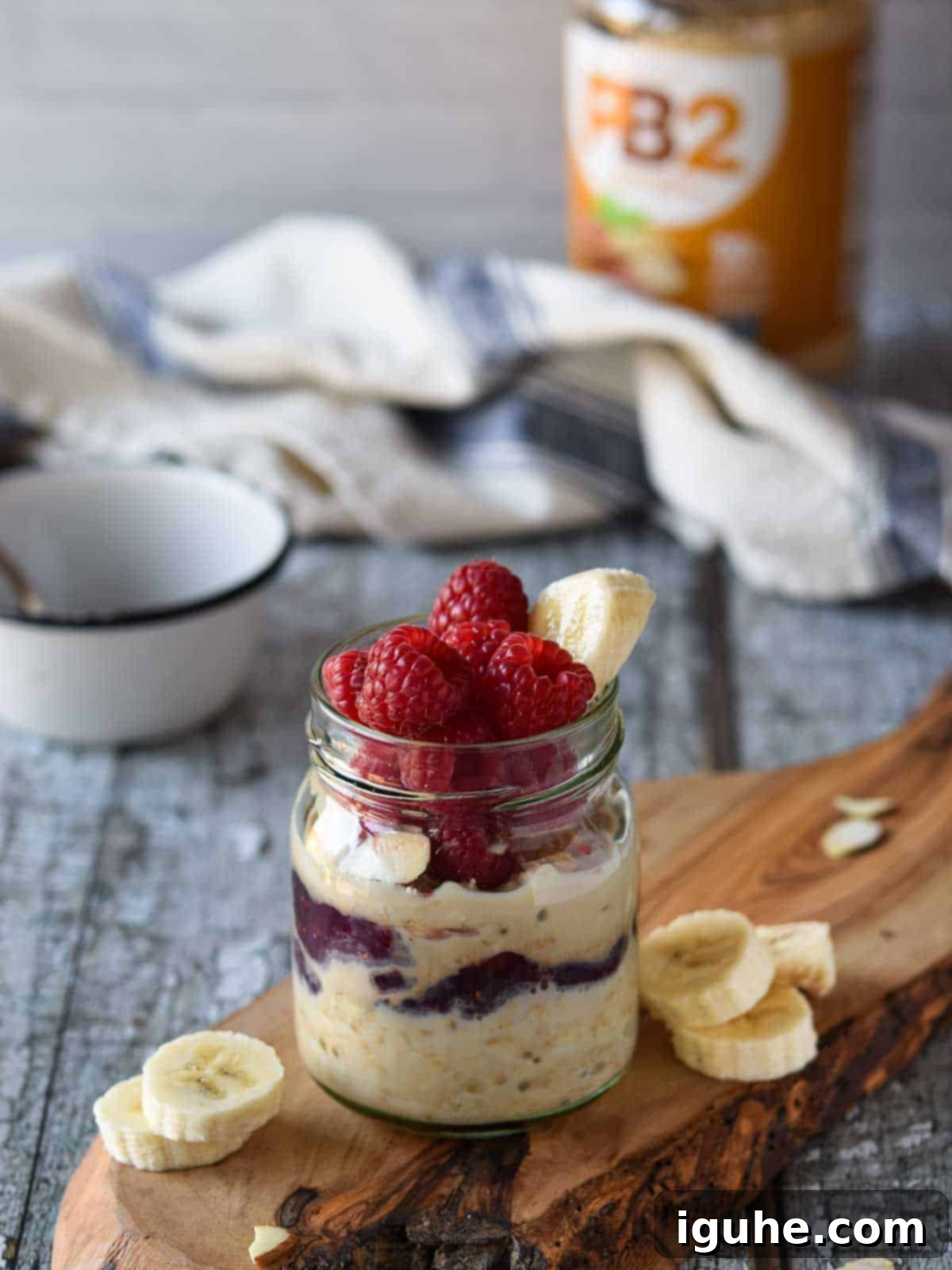 Peanut butter overnight oats in a jar with raspberries and bananas, topped with fresh fruit.